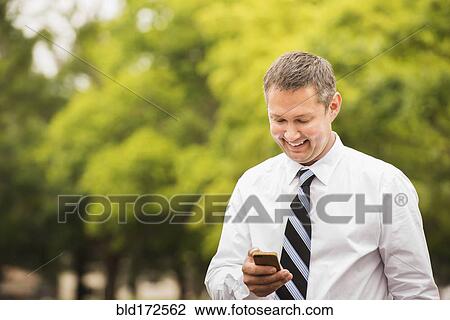 Caucasian businessman using cell phone outdoors View Large Photo Image Stock Image - Caucasian businessman using cell phone outdoors. Fotosearch