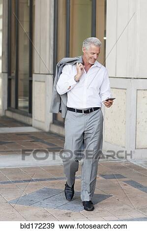 Caucasian businessman using cell phone on city sidewalk View Large Photo Image Stock Photo - Caucasian businessman using cell phone on city sidewalk. Fotosearch