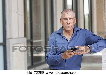 Stock Photo - Caucasian businessman using cell phone in city. Fotosearch