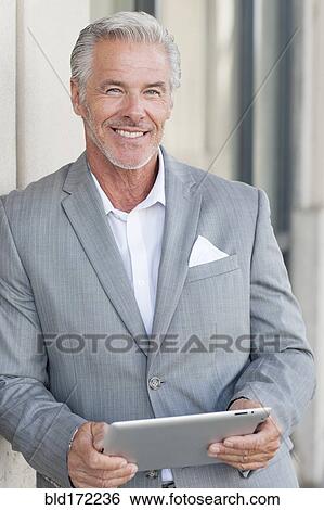 Stock Photograph - Caucasian businessman using digital tablet in city. Fotosearch