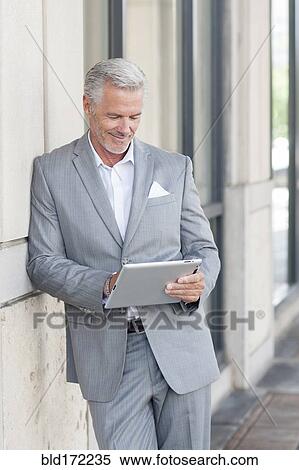 Stock Photography - Caucasian businessman using digital tablet in city. Fotosearch