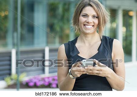 Stock Photograph - Caucasian businesswoman using cell phone in city. Fotosearch