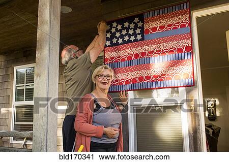 Caucasian couple hanging homemade American flag on porch View Large Photo Image Stock Image - Caucasian couple hanging homemade American flag on porch. Fotosearch