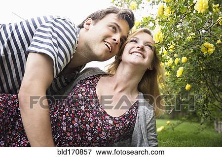 Stock Photo - Caucasian couple hugging in garden. Fotosearch