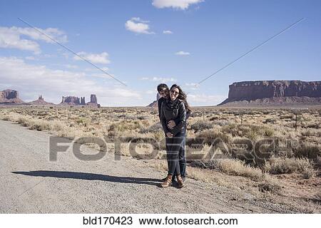 Stock Image - Caucasian couple hugging on desert dirt road. Fotosearch