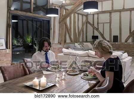 Stock Image - Caucasian couple in dining room of converted barn home. Fotosearch