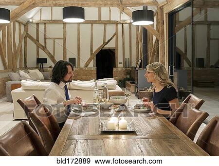 Stock Photo - Caucasian couple in dining room of converted barn home. Fotosearch