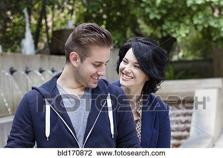 Stock Image - Caucasian couple smiling by urban fountain. Fotosearch