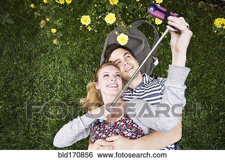 Caucasian couple taking selfie with cell phone in grass View Large Photo Image Stock Photograph - Caucasian couple taking selfie with cell phone in grass. Fotosearch