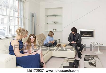 Stock Photo - Caucasian family relaxing in living room. Fotosearch