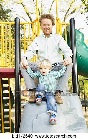Stock Image - Caucasian father and son playing on play structure. Fotosearch