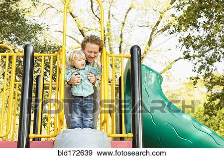 Stock Photo - Caucasian father and son playing on play structure. Fotosearch