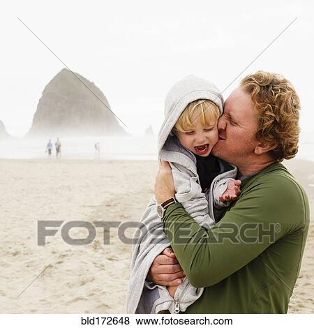 Stock Photo - Caucasian father kissing son on beach. Fotosearch