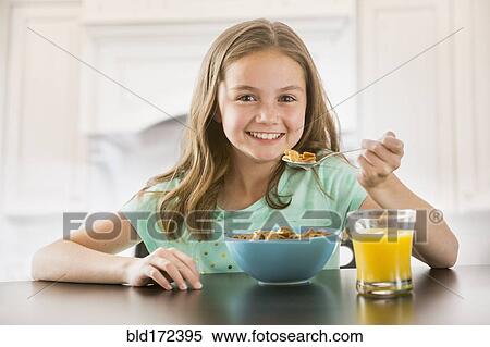 Stock Photography - Caucasian girl eating cereal at table. Fotosearch