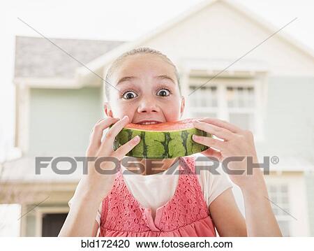 Stock Image - Caucasian girl eating watermelon outdoors. Fotosearch