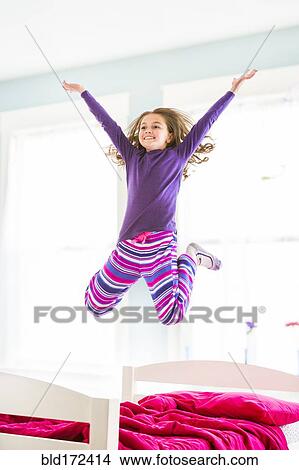 Picture - Caucasian girl jumping on bed. Fotosearch