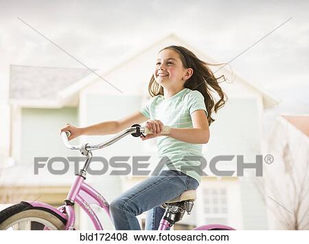 Stock Photo - Caucasian girl riding bicycle in neighborhood. Fotosearch