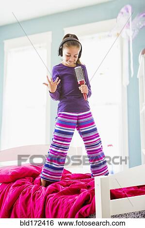 Caucasian girl singing into hairbrush on bed View Large Photo Image Stock Photograph - Caucasian girl singing into hairbrush on bed. Fotosearch