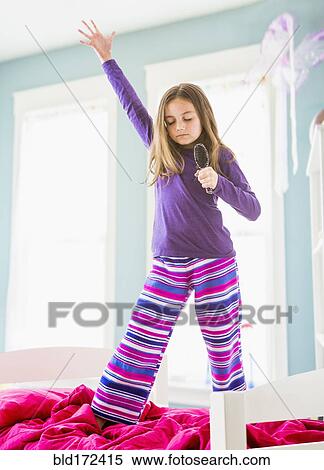 Caucasian girl singing into hairbrush on bed View Large Photo Image Stock Photography - Caucasian girl singing into hairbrush on bed. Fotosearch