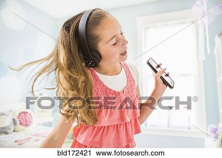 Stock Image - Caucasian girl singing to wireless headphones. Fotosearch