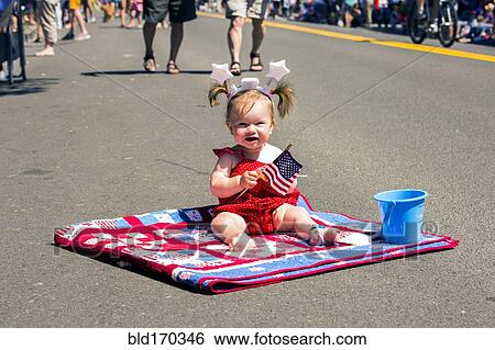 Stock Photograph - Caucasian girl sitting on quit at 4th of July parade. Fotosearch