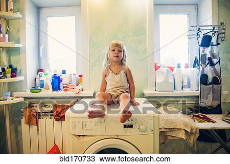 Stock Image - Caucasian girl sitting on washing machine. Fotosearch