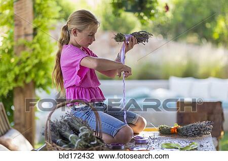 Stock Image - Caucasian girl wrapping dried flower bundle. Fotosearch
