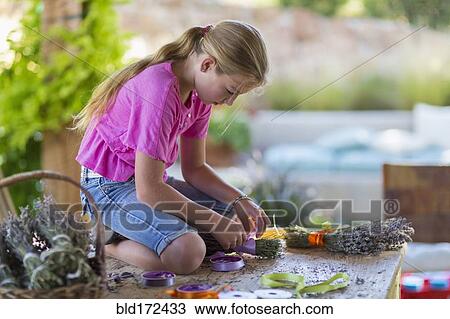 Stock Image - Caucasian girl wrapping dried flower bundle. Fotosearch