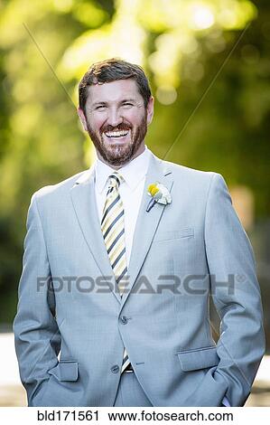 Stock Image - Caucasian groom laughing in garden. Fotosearch