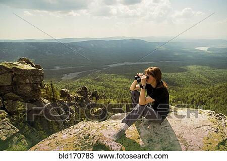 Stock Image - Caucasian hiker admiring remote landscape from rocky hilltop. Fotosearch