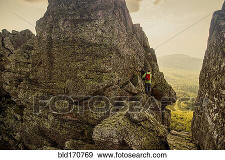 Stock Photo - Caucasian hiker climbing on rock formation. Fotosearch