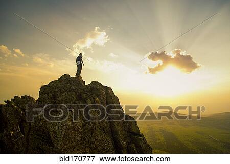 Stock Photo - Caucasian hiker on rocky hilltop in remote landscape. Fotosearch