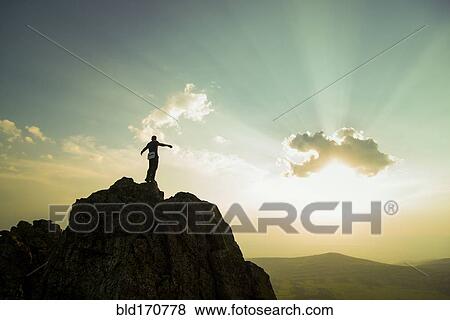 Stock Photo - Caucasian hiker on rocky hilltop in remote landscape. Fotosearch