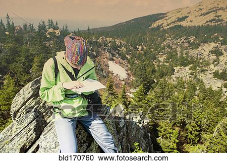 Stock Image - Caucasian hiker reading map on hilltop. Fotosearch