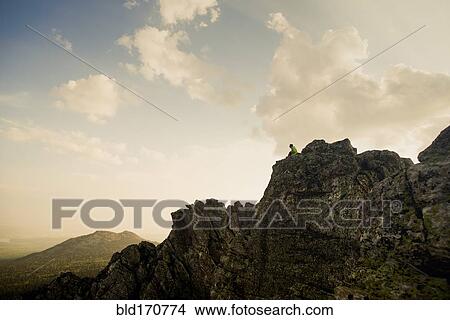 Picture - Caucasian hiker sitting on rocky hilltop. Fotosearch
