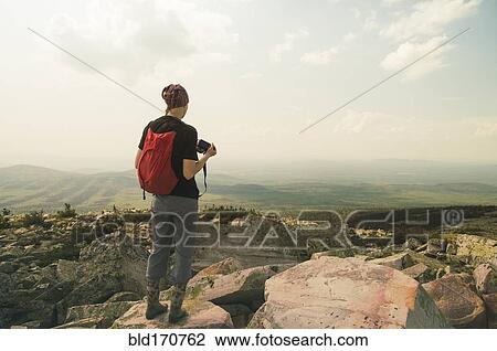 Stock Image - Caucasian hiker standing on rocky hilltop. Fotosearch