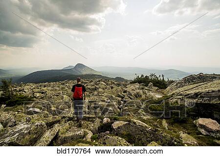 Picture - Caucasian hiker walking in rocky field in remote landscape. Fotosearch