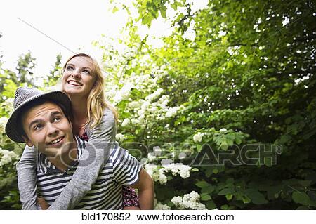 Caucasian man carrying girlfriend piggyback in garden View Large Photo Image Stock Image - Caucasian man carrying girlfriend piggyback in garden. Fotosearch
