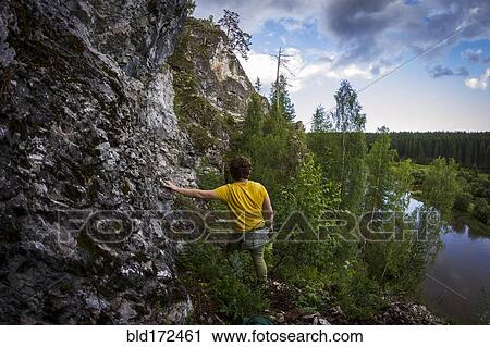 Stock Image - Caucasian man climbing sheer rock cliff. Fotosearch