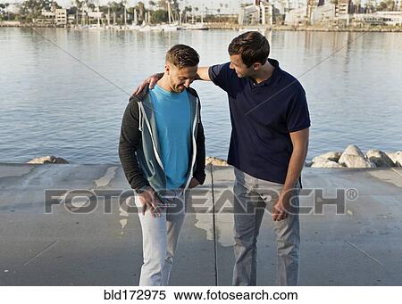 Stock Photography - Caucasian man comforting friend at waterfront. Fotosearch