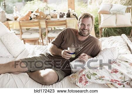 Caucasian man drinking on bed View Large Photo Image Stock Image - Caucasian man drinking on bed. Fotosearch