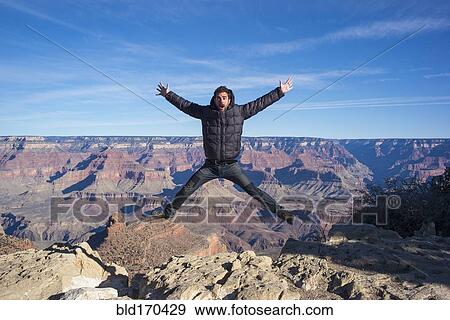 Stock Photo - Caucasian man jumping at Grand Canyon, Arizona, United States. Fotosearch