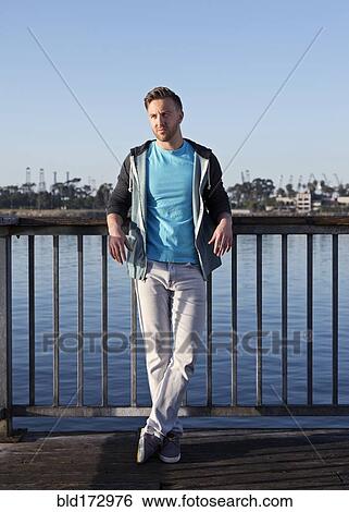 Stock Photograph - Caucasian man leaning at waterfront. Fotosearch