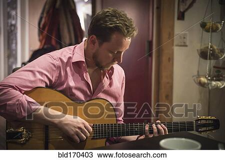 Stock Image - Caucasian man playing guitar. Fotosearch