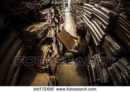 Stock Photograph - Caucasian man reading book in library archive. Fotosearch