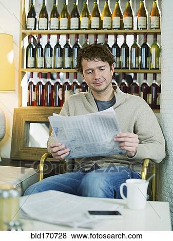 Stock Photo - Caucasian man reading newspaper in restaurant. Fotosearch