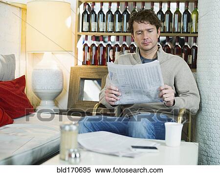 Stock Photography - Caucasian man reading newspaper in armchair. Fotosearch