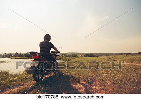Caucasian man riding motorcycle in rural field View Large Photo Image Stock Photo - Caucasian man riding motorcycle in rural field. Fotosearch
