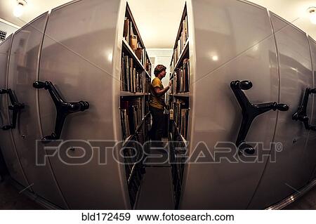 Stock Photo - Caucasian man searching old newspapers in library archive. Fotosearch