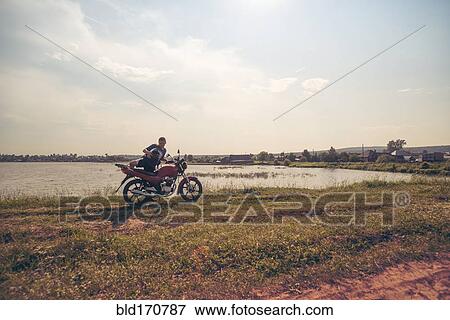 Caucasian man sitting on motorcycle in park View Large Photo Image Stock Photo - Caucasian man sitting on motorcycle in park. Fotosearch